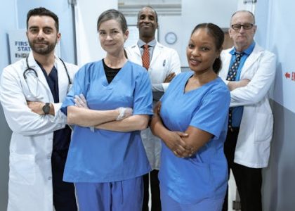 pexels-photo-6129507-6129507 A diverse team of doctors and nurses smiling confidently in a hospital setting.